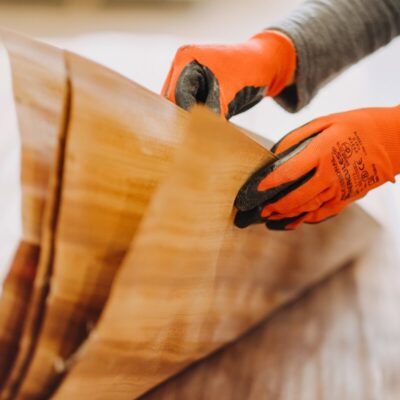 Osoba w rękawicach układa sklejki okleinowane i płyty stolarskie.