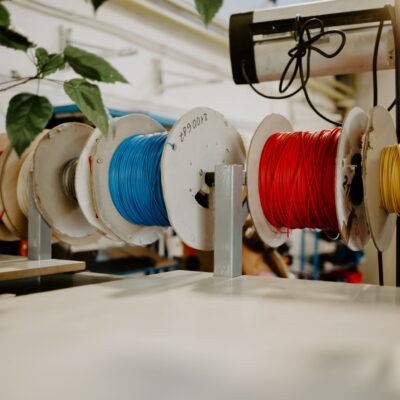 Szpule z kolorowymi kablami wiszą na stojaku w warsztacie.