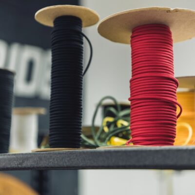 Na półce stoją szpule z nawiniętymi kablami w różnych kolorach.