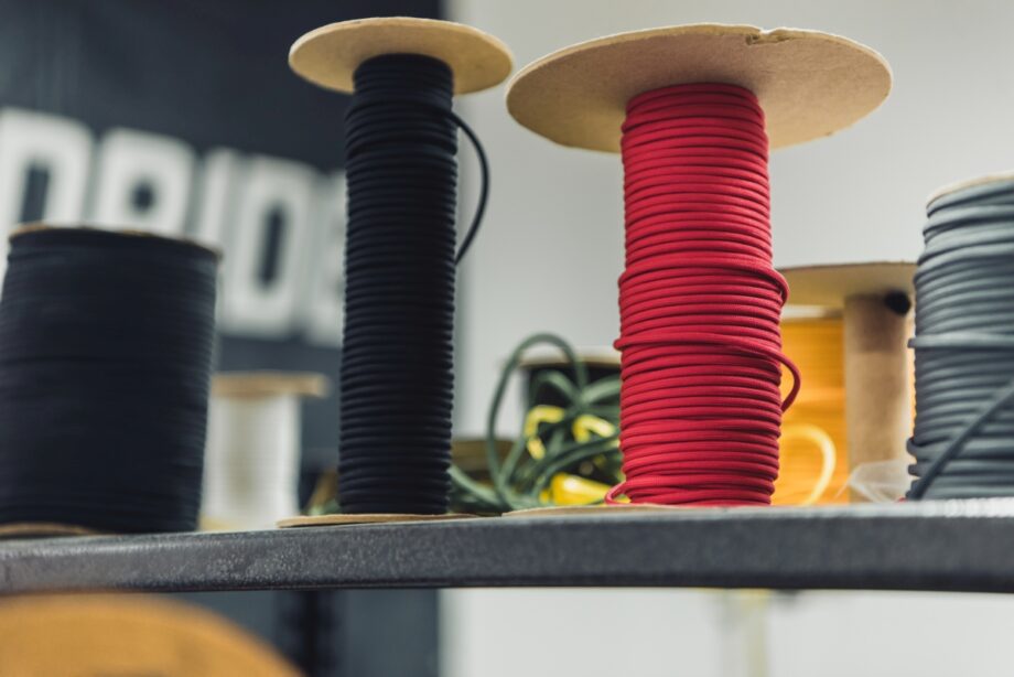 Na półce stoją szpule z nawiniętymi kablami w różnych kolorach.